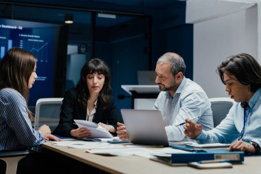 Üst düzey bir şirket yönetim kurulundaki yatırım riskini değerlendiren beyin fırtınası oturumunda aralarında yönetici ve asistanların da yer aldığı dört profesyonel işbirliği yapıyor. Stratejik toplantı, lüks ofis ortamında takım çalışması ve analizleri gösteriyor..