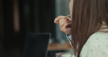 Beyaz saçlı genç bir stajyerin öğle yemeğinde chia pudingi yerken yavaş çekim videosu. Kamera elindeki pudingin yakın çekimini yakalar, sonra yemek yerken ve iş arkadaşlarıyla konuşurken yüzüne bakar..