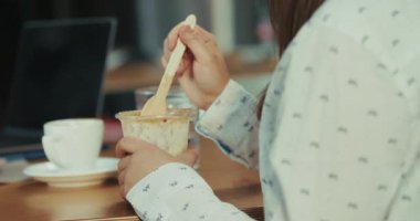 Kafkasyalı açık renk saçlı bir stajyerin öğle yemeğinde chia pudingi yerken yavaş çekim videosu. Kamera elindeki pudingin yakın çekimini yakalar, sonra yemek yerken ve iş arkadaşlarıyla konuşurken yüzüne bakar..