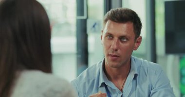 Kafkasyalı bir adamın sağlıklı salata yemeğini güzel yeşil ve doğal ışıklandırmalı, rahat bir ofis kafeteryasında yediği yavaş çekim videosu. Bir iş arkadaşı onlara doğru yürür ve masalarına katılır..