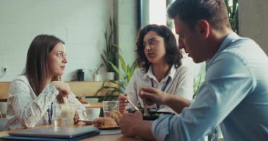 Üç Kafkas stajyer takım arkadaşı, aydınlık, güneşli bir ofis kafeteryasında ağır çekimde dostça bir öğle yemeğini paylaşıyor. Sahne, iş yeri arkadaşlığını ve takım arkadaşlığını öğle arasında yakalıyor..