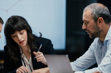 Kafkasyalı gevşek yöneticiler ve resmi giyinmiş ortaklar modern yapay ofisteki büyük ekranda ilerleme raporunu tartışıyorlar, işbirlikçi iş beyin fırtınası oturumu