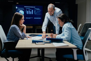 Modern ofiste kıdemli Kafkas yöneticisinin rehberlik ettiği şirket danışmanlığı sahnesi, ekranda ilerleme, profesyonel gelişim ve kurumsal kültür eğitimi konularında tartışmalar