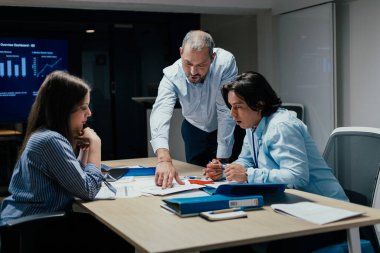 Modern ofiste kıdemli Kafkas yöneticisinin rehberlik ettiği şirket danışmanlığı sahnesi, ekranda ilerleme, profesyonel gelişim ve kurumsal kültür eğitimi konularında tartışmalar