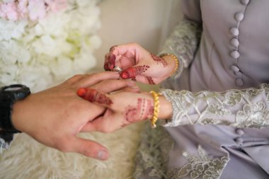 Malezyalı gelin damadın parmağına yüzük takıyor. Gelin, damadın sol parmağına alyans takar, Müslüman düğünü, düğün posterleri, elini kapat.