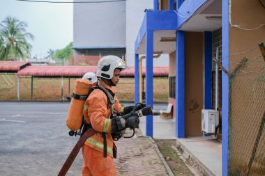 Muadzam Şah, Malezya - 10 Ağustos 2023: İtfaiyeci bir ateşe suyla saldırıyor. İtfaiyeci ekibi, 2023 Ajanslar Arası Felaket Eğitim Programı 'nda yangın tatbikatı sırasında çalışıyor.