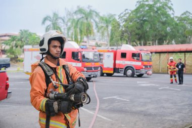 Muadzam Şah, Malezya - 10 Ağustos 2023: İtfaiyeci bir ateşe suyla saldırıyor. İtfaiyeci ekibi, 2023 Ajanslar Arası Felaket Eğitim Programı 'nda yangın tatbikatı sırasında çalışıyor.