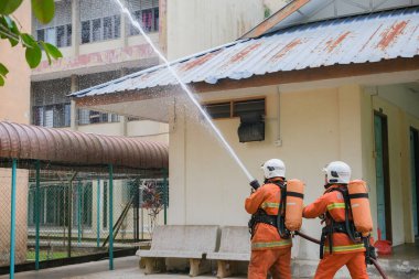 Muadzam Şah, Malezya - 10 Ağustos 2023: İtfaiyeci bir ateşe suyla saldırıyor. İtfaiyeci ekibi, 2023 Ajanslar Arası Felaket Eğitim Programı 'nda yangın tatbikatı sırasında çalışıyor.