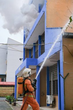 Muadzam Şah, Malezya - 10 Ağustos 2023: İtfaiyeci bir ateşe suyla saldırıyor. İtfaiyeci ekibi, 2023 Ajanslar Arası Felaket Eğitim Programı 'nda yangın tatbikatı sırasında çalışıyor.