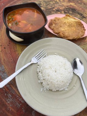 Omlet ve beyaz pirinç baharatlı tomyam ile sıcak ve ekşi çorba yerler.