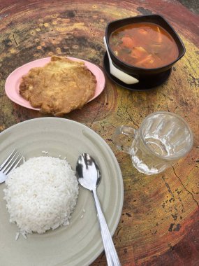 Omlet ve beyaz pirinç baharatlı tomyam ile sıcak ve ekşi çorba yerler.