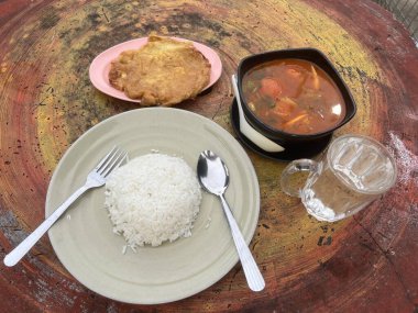 Omlet ve beyaz pirinç baharatlı tomyam ile sıcak ve ekşi çorba yerler.