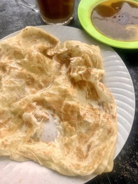 Öğleden sonra atıştırmak için roti canai yemek.