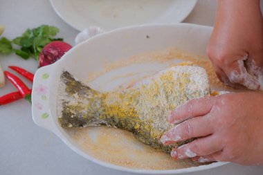 Kadın şefin elleri balık yemi hazırlıyor.