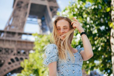 Paris 'teki Eyfel Kulesi' nin yanında mavi elbiseli, güzel ve zarif bir kadın.