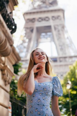 Paris 'teki Eyfel Kulesi' nin yanında mavi elbiseli, güzel ve zarif bir kadın.