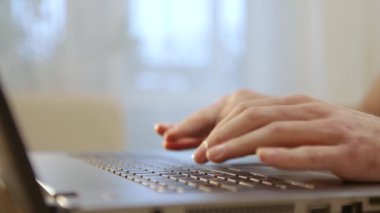 Dizüstü bilgisayar kullanan, yazı yazan genç bir adamın elleri