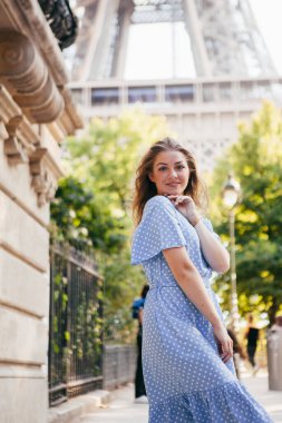 Elbiseli güzel bir kız Eyfel Kulesi 'nin yanında poz veriyor.