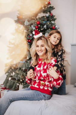 Genç güzel anne kızıyla birlikte Noel ağacının yanında.