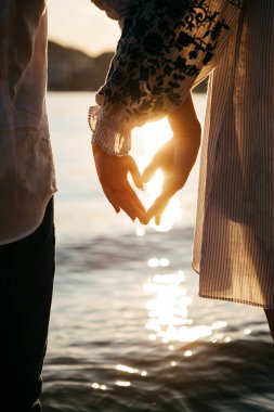 Gün batımında genç bir çift suyun kenarında