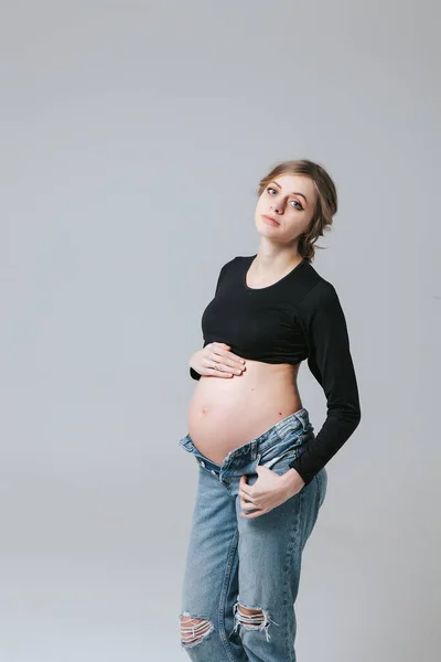 穿着白色背景牛仔裤的年轻怀孕女孩 — 图库照片
