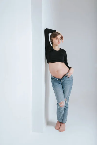 穿着白色背景牛仔裤的年轻怀孕女孩 — 图库照片