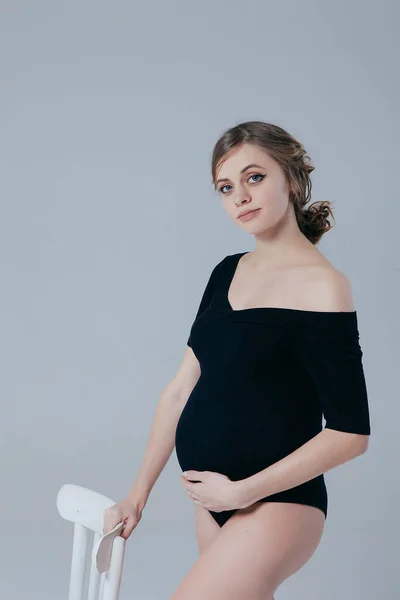 一个穿着黑色紧身衣穿着白色背景衣服的怀孕少女 — 图库照片