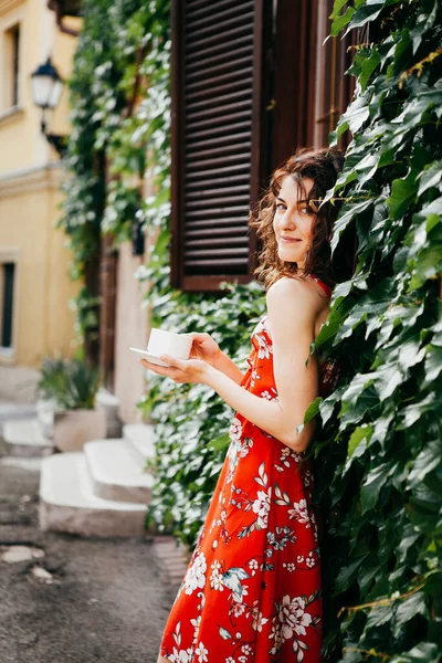 穿着红色连衣裙的年轻貌美的女人 拿着一杯欧洲水壶 — 图库照片