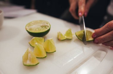 slicing a lime into pieces with a knife