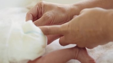 Terapistin elleri bebeğin küçük bacağını ovuyor. Küçük bebek ayağına masaj yapan bir masör. Çocukluk konsepti. Evde kal. Ayak masajı. Yatağa bebek ayak masajı.