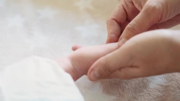 優しい母親の手で小さな新生児の足の閉鎖ショット セラピストの手は幼児の小さな足をこすります マッサージ小さな赤ちゃん足をマッサージ — ストック動画