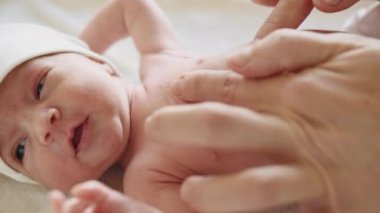 Kolik önleme. Yeni doğan bebeğe karın masajı yapan kadın eller. Yeni doğmuş bebek bakım konsepti. Yeni doğan bebeğe masaj yapan kadın elleri. Kafkasyalı güzel bir bebek arkada yatıyor. Portre