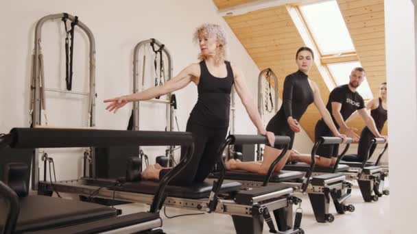 Skicklig Senior Kvinnlig Tränare Kvinna Framför Split Pilates Reformator Klassen — Stockvideo