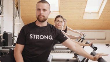 Büyük bir spor salonunun eğitmeni. Yakışıklı sakallı erkek eğitmen bayan müşterilerini pilates reformist stüdyosunda sırayla otururken gösteriyor. Rehabilitasyon, sağlıklı yaşam tarzı