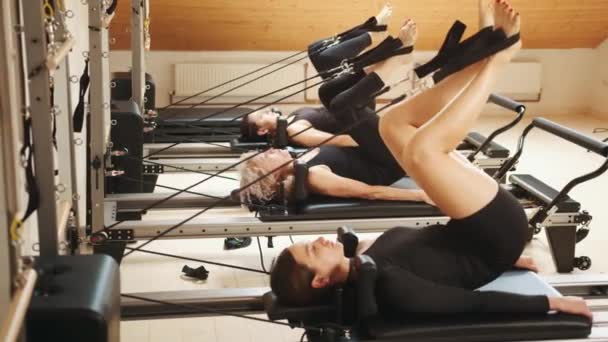 一群漂亮的女人穿着黑色运动服 在室内的一个工作室里用普拉提机做改革者伸展运动 康复和健康的生活方式 肌肉释放的概念 — 图库视频影像