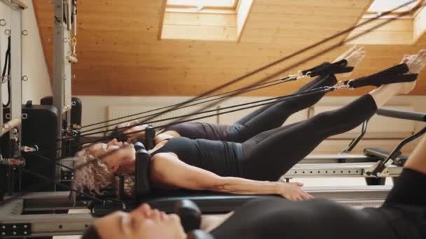 康复和健康的生活方式 肌肉释放的概念 在现代演播室的个人锻炼中 一组女性在普拉提改革者上连续做腹肌运动 — 图库视频影像