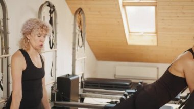 Spor merkezi, pilates stüdyosu. Olgun kadın antrenör, reformist yatakta egzersiz yapan kadın müşteriye koçluk yapıyor. Rehabilitasyon, sağlıklı yaşam tarzı, küçük işletme kavramı