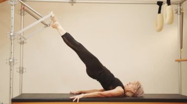 Cadillac 'ta, rehabilitasyon merkezindeki fitness ekipmanında yaşlı kadınların yaptığı bir dizi pilates egzersizi. Aktif ve sağlıklı yaşam rehabilitasyon konsepti. Pilates hocası..