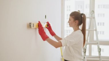 Repair, building and home concept - smiling couple building new home using spirit level to measure. Young woman using leveling tool at home. A happy family is renovating a purchased apartment