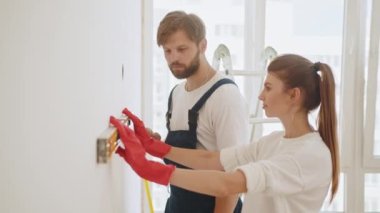 Young woman using leveling tool at home. A happy family is renovating a purchased apartment. Repair, building and home concept - smiling couple building new home using spirit level to measure