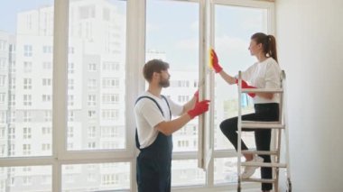 Couple housekeeping and working together to clean glass. Cleaning products, house cleaning and washing glass door with facial happiness. Cleaning, washing Windows by special sponge.