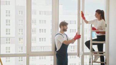 Employees of a cleaning company clean a house or apartment. A man and a woman wash windows in an apartment after repairs. Cleaning an apartment or house. The family cleans the windows.
