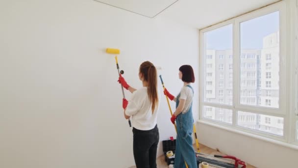 Duas Jovens Mulheres Pintando Parede Com Rolo Pintura Enquanto Mulheres — Vídeo de Stock