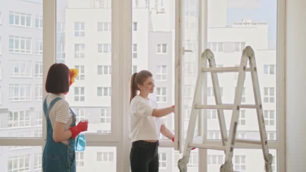 Две Положительные Женщины Убирают Комнату Вместе Женщина Перчатки Моющие Окно — стоковое видео