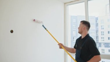 Ressam adam. Mavi tulumlu sakallı bir inşaat işçisi koridora bir duvar boyuyor. O bir silindir kullanır. Yeni dairesinde duvar boyayan bir adam. Yenileme ve dekorasyon konsepti