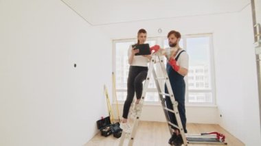 Genç çift evde renk paleti ve mobilya seçiyor. Ev, taşınma, dekorasyon, yenileme ve duvar boyama konsepti. Çift tablet bilgisayarda apartman yenileme planını tartışıyor