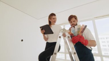 Çift tablet bilgisayarda apartman yenileme planını tartışıyor. Genç çift evde renk paleti ve mobilya seçiyor. Ev, taşınma, dekorasyon, yenileme ve duvar boyama konsepti