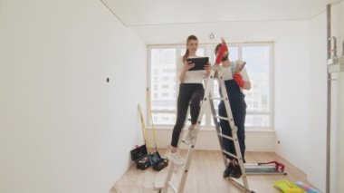 Çift tablet bilgisayarda apartman yenileme planını tartışıyor. Genç çift evde renk paleti ve mobilya seçiyor. Ev, taşınma, dekorasyon, yenileme ve duvar boyama konsepti.