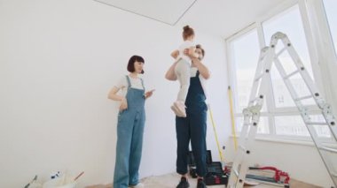 Apartmanda tamirat var. Mutlu aile evlerini yeniliyor. Mutlu, genç bir ailenin birlikte vakit geçirmesi boyama ve yenileme odasından sonra dinlenmesi. Çocuk anne ve babasına sıkıca sarılıyor.