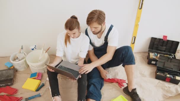 Satisfied Young Couple Look Laptop Planning New Interior Sit Floor — ストック動画